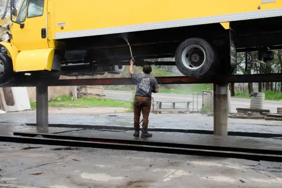 A worker washing down the side of a yellow box truck